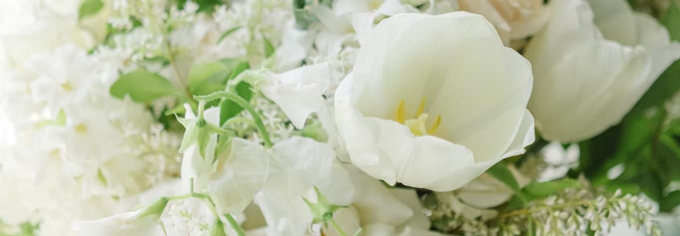 A close arrangement of white wedding flowers including tulips and roses
